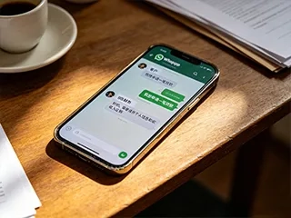 A mobile phone with WhatsApp open is on the table.