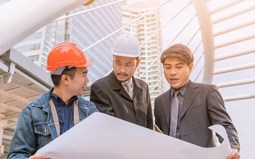 Three men are looking at construction site blueprints.